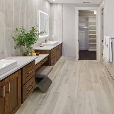 Contemporary bathroom with wood vanity on white countertops and vessel sinks.